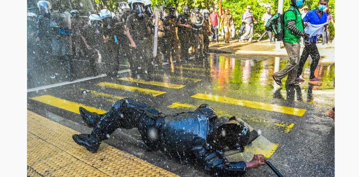 Un miembro del personal de seguridad cae mientras la policía utiliza cañones de agua para dispersar a los manifestantes antigubernamentales durante una manifestación en Colombo, Sri Lanka.