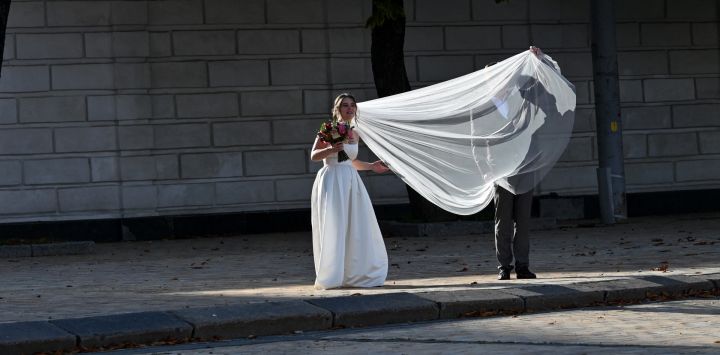 Un novio endereza el velo de novia en el centro de la capital ucraniana de Kiev, justo después de su boda.