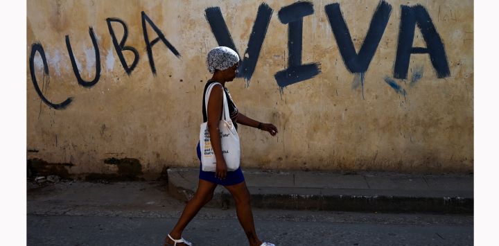 Una mujer pasa junto a un grafiti que dice "Cuba viva" en una calle de La Habana.