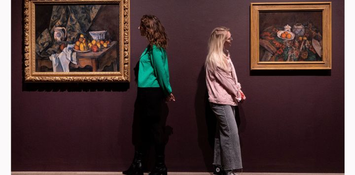 Miembros del personal posan para una fotografía con los cuadros "Naturaleza muerta con manzanas y melocotones" (izq.) y "Naturaleza muerta con jarra de jengibre, azucarero y naranjas", del artista francés Paul Cezanne, durante un avance de prensa antes de la próxima exposición "The EY Exhibition: Cezanne' en la galería Tate Modern de Londres.