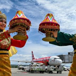 Bailarines tradicionales posan junto a un avión de pasajeros de AirAsia que llegó desde Malasia por primera vez desde que se reabrió la ruta después de estar suspendida durante casi tres años debido a la pandemia de Covid-19, en el aeropuerto internacional Sultán Iskandar Muda en Blang Bintang, provincia de Aceh, Indonesia. | Foto:CHAIDEER MAHYUDDIN / AFP