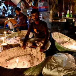 Vendedores utilizan velas en un mercado de pescado durante un apagón en Dhaka. - Al menos 130 millones de personas en Bangladesh se quedaron sin electricidad después de que un fallo en la red eléctrica provocara apagones generalizados, según informó la compañía eléctrica del gobierno. | Foto:MUNIR UZ ZAMAN / AFP