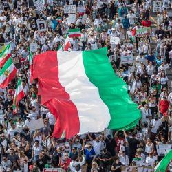 Manifestantes sostienen la bandera de Irán durante una protesta por Mahsa Amini, que murió bajo la custodia de la policía de la moral de Irán, en Los Ángeles, California. - La muerte de Amini tras su detención por la policía de la moral iraní ha desencadenado una ola de disturbios desde que la joven de 22 años muriera tras su arresto por supuestamente no respetar el estricto código de vestimenta iraní para las mujeres. | Foto:Apu Gomes / AFP