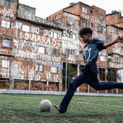 Un niño juega al fútbol en un campo de la favela Morro da Lua, en Sao Paulo, Brasil. | Foto:ERNESTO BENAVIDES / AFP