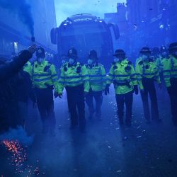 Agentes de policía forman una línea de protección mientras un entrenador del equipo llega antes del partido de fútbol de la Premier League inglesa entre el Everton y el Manchester United en Goodison Park en Liverpool, noroeste de Inglaterra. | Foto:OLI SCARFF / AFP