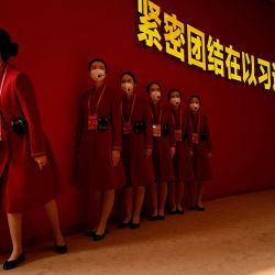 Los asistentes esperan a los visitantes de la exposición titulada "Forjando hacia adelante en la nueva era", que muestra los logros del país durante sus dos últimos mandatos, en el Centro de Exposiciones de Pekín en Pekín, China. | Foto:Noel Celis / AFP