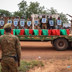 Militares de Burkina Faso sostienen los retratos de los soldados detrás de los ataúdes durante el entierro de los soldados muertos en Gaskinde, en Uagadugú. - En la emboscada de Gaskinde, reivindicada por Al Qaeda, murieron oficialmente 37 personas, entre ellas 27 soldados. | Foto:OLYMPIA DE MAISMONT / AFP