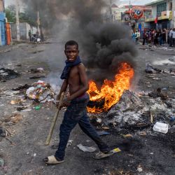 Un hombre pasa por delante de una barricada en llamas durante una protesta contra el primer ministro haitiano Ariel Henry que pide su dimisión, en Puerto Príncipe, Haití. | Foto:Richard Pierrin / AFP