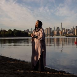 Una mujer reza mientras sostiene un recipiente de agua traído de Puerto Rico durante una ceremonia del Día de los Pueblos Indígenas al amanecer en la isla de Randall en la ciudad de Nueva York. | Foto:YUKI IWAMURA / AFP