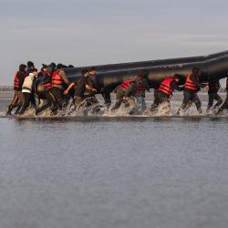 Los migrantes llevan una embarcación de contrabando sobre sus hombros mientras se preparan para embarcar en la playa de Gravelines, cerca de Dunkerque, en el norte de Francia, en un intento de cruzar el Canal de la Mancha. | Foto:Sameer Al-Doumy / AFP