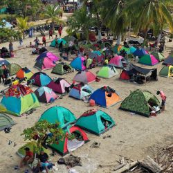 Migrantes varados acampan en una playa mientras esperan subir a un barco en la ciudad portuaria colombiana de Necoclí, para cruzar a la vecina Panamá y continuar su viaje hacia Estados Unidos. | Foto:Danilo Gomez / AFP