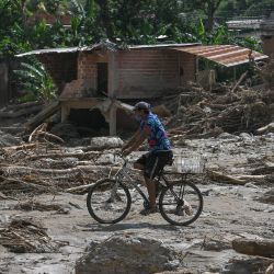 Un hombre monta una bicicleta entre los escombros de las casas destruidas días después de un devastador deslizamiento de tierra en la ciudad de Las Tejerías, estado de Aragua, Venezuela. | Foto:Federico Parra / AFP