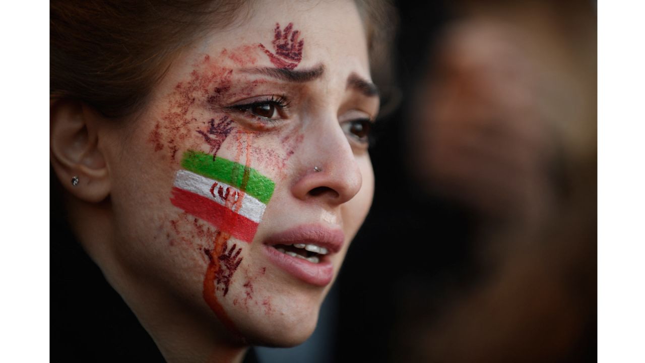 Una manifestante con una bandera iraní y las manos rojas pintadas en la cara asiste a una concentración de apoyo a las protestas iraníes, tras la muerte de la iraní Mahsa Amini en Irán. | Foto:JULIEN DE ROSA / AFP
