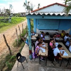 Estudiantes asisten a una clase en la puerta de una casa en La Coloma, provincia de Pinar del Río, Cuba, luego del paso del poderoso huracán Ian. | Foto:YAMIL LAGE / AFP