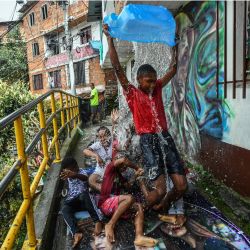 Niños de la zona juegan con el agua en el barrio de la Comuna 13 de Medellín, Colombia. | Foto:JOAQUIN SARMIENTO / AFP