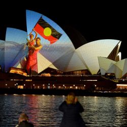 Las velas de la Ópera de Sídney se ven iluminadas con una proyección de obras de arte de vídeo para iniciar las celebraciones de un año de duración para el 50 aniversario del monumento, en Sídney, Australia. | Foto:Muhammad Farooq / AFP