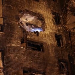 Los bomberos miran desde un edificio de apartamentos de nueve pisos parcialmente destruido después de que un avión militar Sukhoi Su-34 se estrellara en el patio de una zona residencial en la ciudad de Yeysk, en el suroeste de Rusia. | Foto:STRINGER / AFP