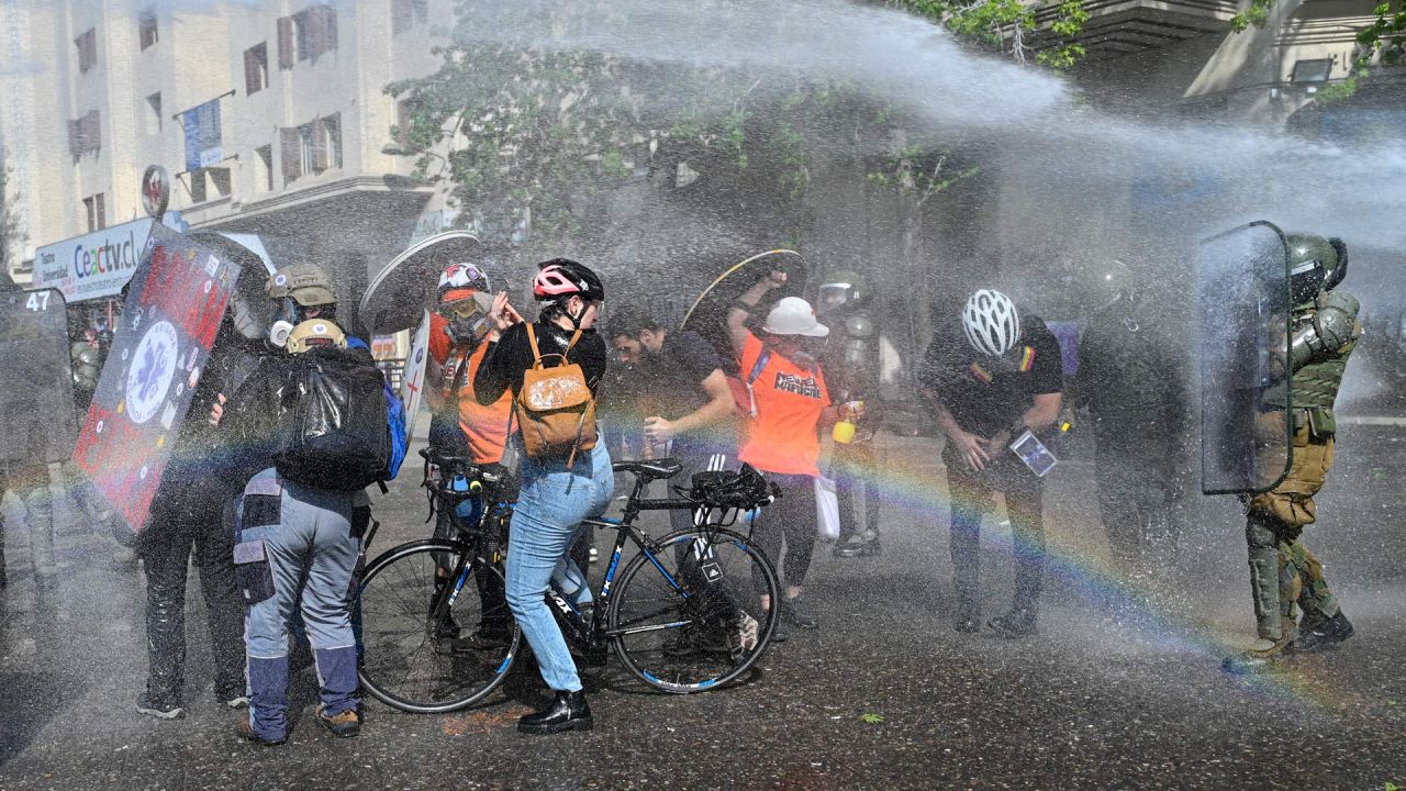 Manifestantes son rociados con cañones de agua durante los enfrentamientos con la policía antidisturbios que estallaron en una protesta en el tercer aniversario de un levantamiento social contra el aumento de los precios de los servicios públicos, en los alrededores de la plaza Baquedano en Santiago, Chile. | Foto:MARTIN BERNETTI / AFP