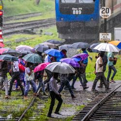 Peatones con paraguas caminan a lo largo de un cruce de ferrocarril durante un fuerte aguacero en Colombo, Sri Lanka. | Foto:ISHARA S. KODIKARA / AFP
