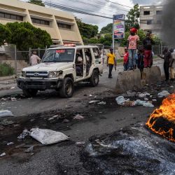 Un coche de policía pasa junto a un neumático en llamas mientras los manifestantes protestan para rechazar una fuerza militar internacional solicitada por el gobierno en Puerto Príncipe, Haití. | Foto:Richard Pierrin / AFP