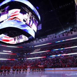 Los Chicago Blackhawks observan la interpretación del himno nacional antes del partido contra los Detroit Red Wings en el United Center en Chicago, Illinois. | Foto:Michael Reaves/Getty Images/AFP
