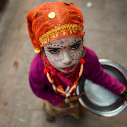 Un niño se maquilla como imitador mientras pide limosna a los transeúntes en una zona de mercado antes del festival de Diwali en Nueva Delhi, India. | Foto:Sajjad Hussain / AFP
