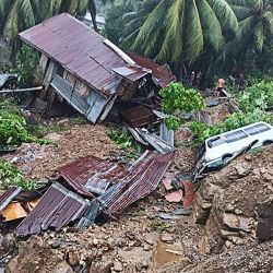 Esta foto tomada y recibida del Equipo de Desembarco del Batallón de Marines de Filipinas muestra a un residente junto a una casa y un vehículo dañados tras un desprendimiento de tierras debido a las fuertes lluvias provocadas por la tormenta tropical Nalgae en la ciudad de Parang, en la provincia de Maguindanao, en el sur de Filipinas. | Foto:MARINES BATTALION LANDING TEAM 5 / AFP