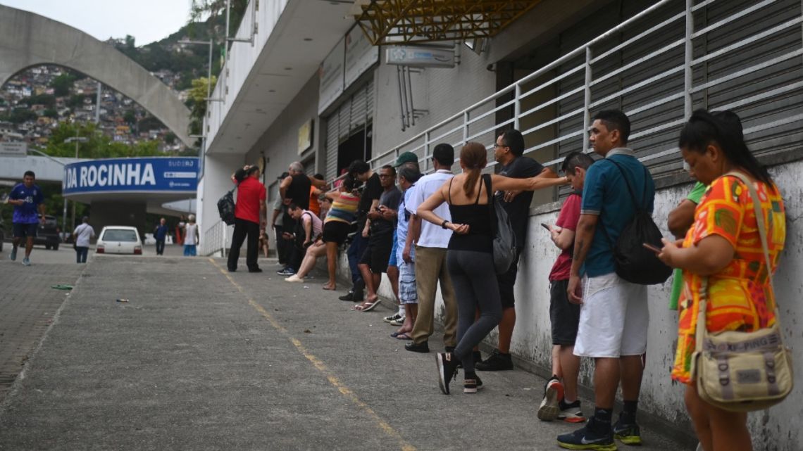 People queue outside a polling station near Rocinha, Rio de Janeiro's biggest favela, on October 30, 2022, during the presidential run-off election. After a bitterly divisive campaign and inconclusive first-round vote, Brazil elects its next president in a cliffhanger runoff between far-right incumbent Jair Bolsonaro and veteran leftist Luiz Inácio Lula da Silva. 