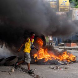 Un hombre corre junto a un montón de neumáticos en llamas mientras los manifestantes exigen la liberación del periodista haitiano Robest Dimanche, que fue detenido mientras cubría una protesta, en Puerto Príncipe, Haití. | Foto:Richard Pierrin / AFP
