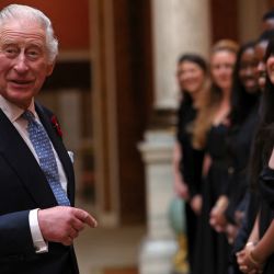 El rey Carlos III de Gran Bretaña reacciona mientras se reúne con miembros del Westend Gospel Choir después de una ceremonia que conmemora el 50 aniversario del reasentamiento de los asiáticos británicos de Uganda, en el Palacio de Buckingham en Londres. | Foto:ISABEL INFANTES / varias fuentes / AFP