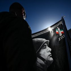 Un participante sostiene una bandera con un retrato de Benito Mussolini durante una marcha hacia el cementerio de San Cassiano, lugar de enterramiento de Benito Mussolini, en Predappio. | Foto:PIERO CRUCIATTI / AFP
