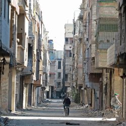 Unos hombres pasan en bicicleta por delante de edificios dañados en el campo de refugiados de Yarmuk, en los suburbios del sur de la capital siria, Damasco. - El régimen del presidente de Siria, Bashar al-Assad, ha reconquistado un vasto territorio de los rebeldes y los yihadistas en el conflicto que comenzó en 2011, incluida la reconquista del campo palestino y los suburbios adyacentes en mayo de 2018, tras un asalto pulverizador que duró casi un mes. | Foto:LOUAI BESHARA / AFP