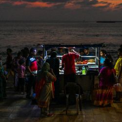 En esta foto los visitantes compran comida callejera a un vendedor de langostinos y cangrejos desde un carrito en el paseo de Galle Face en Colombo, Sri Lanka. | Foto:ISHARA S. KODIKARA / AFP