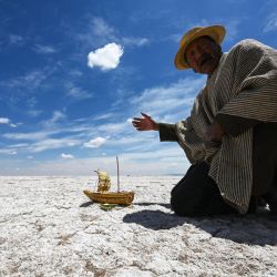 Félix Mauricio, miembro de la comunidad indígena Uru Murato, muestra una réplica en miniatura de una embarcación conocida como "bote de totora" en un desierto en el lugar del antiguo lago Poopo, cerca del pueblo de Punaca Tinta María, provincia de Oruro, Bolivia. | Foto:AIZAR RALDES / AFP