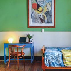  El cuarto de la mayor de sus hijas linda con el hall de entrada dejando entrever, desde una señorial puerta de doble hoja, una paleta de verdes y azules y una obra de Luis F. Benedit.