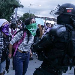 Grupos feministas gritan consignas mientras se enfrentan a la policía antidisturbios, durante una protesta contra el presunto abuso sexual de una mujer menor de edad dentro de una estación de transporte público de Transmilenio, en Bogotá, Colombia. | Foto:Andrea Ariza / AFP
