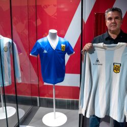 El coleccionista argentino Javier Maluf posa en Doha con la camiseta que usó Diego Maradona durante un partido amistoso contra Inglaterra en mayo de 1980 y junto a la camiseta azul que usó Maradona cuando marcó dos goles en la famosa victoria por 2-1 sobre Inglaterra en el Mundial de 1986. | Foto:IVAN PISARENKO / AFP
