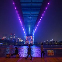 La gente camina por un paseo a lo largo del río Huangpu bajo el puente Lupu en Shanghái. | Foto:HECTOR RETAMAL / AFP