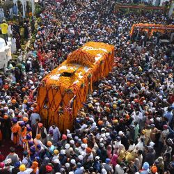 Los devotos sijs se reúnen alrededor de un autobús que lleva el Guru Granth Sahib (libro sagrado del sijismo) durante una procesión religiosa con motivo del aniversario del nacimiento de Guru Nanak Dev, el fundador del sijismo, en Nankana Sahib, Pakistán. | Foto:Arif ALI / AFP