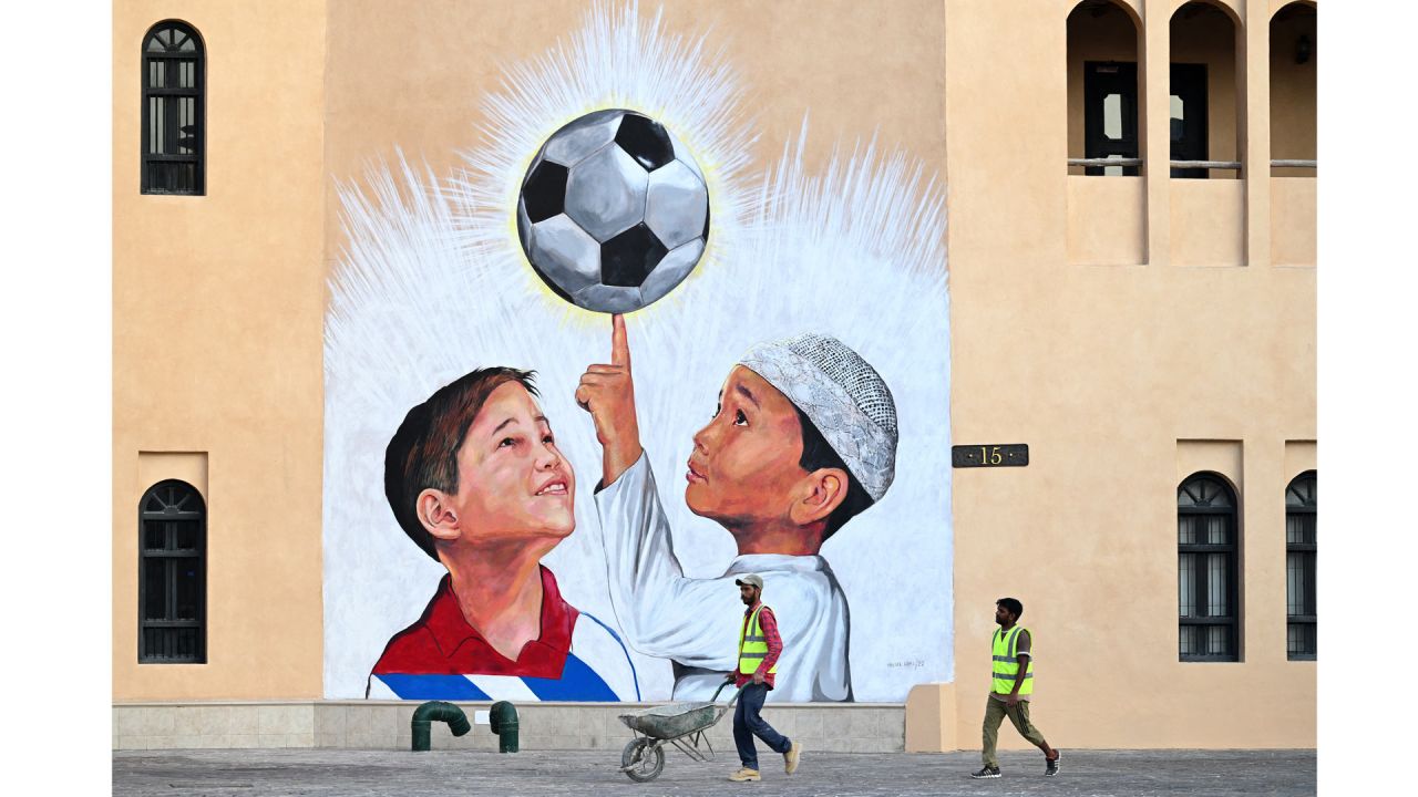 Un trabajador empuja una carretilla junto a un mural en Doha, antes del torneo de fútbol de la Copa Mundial de la FIFA Qatar 2022. | Foto:GABRIEL BOUYS / AFP