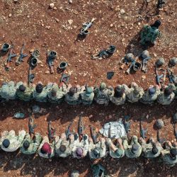 Esta vista aérea muestra a combatientes afiliados al grupo rebelde sirio "Hayat Tahrir al-Sham" (HTS), realizando sus oraciones durante un ejercicio militar sobre tácticas de ataque con munición real, en las afueras de la provincia noroccidental de Idlib. | Foto:OMAR HAJ KADOUR / AFP