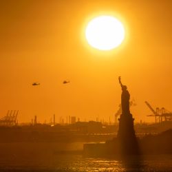 Los helicópteros vuelan mientras el sol se pone detrás de la Estatua de la Libertad en Nueva York. | Foto:ANGELA WEISS / AFP
