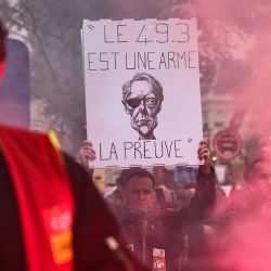 Un manifestante sostiene una pancarta con la imagen de la primera ministra francesa, Elisabeth Borne, en la que se lee "El 49.3 (artículo de la Constitución) es un arma, la prueba" durante una manifestación en el marco de una huelga nacional durante una jornada de movilización nacional e interprofesional convocada por el sindicato CGT en París. | Foto:THOMAS SAMSON / AFP