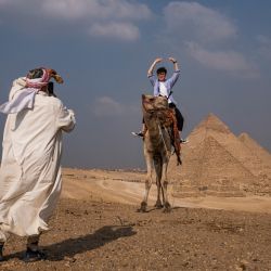 Un turista montado en un camello posa para una foto desde un promontorio con vistas a la necrópolis de las pirámides de Guiza en las afueras de la capital de Egipto. | Foto:AMIR MAKAR / AFP