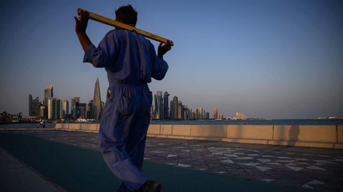 A worker walks on the Corniche in Doha on November 15, 2022, ahead of the Qatar 2022 World Cup football tournament.