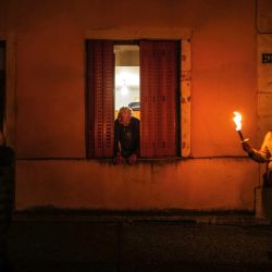Un anciano mira por una ventana mientras los participantes con velas en la mano participan en el tradicional acto de "las Sarmentelles", que anuncia el inicio de la edición del vino "Beaujolais Nouveau" 2022, en las calles de Beaujeu, Francia. | Foto:OLIVIER CHASSIGNOLE / AFP