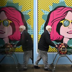 Un hombre empuja un carro frente a unos tableros de colores colocados en una tienda cerrada en Chester, Gran Bretaña. | Foto:OLI SCARFF / AFP