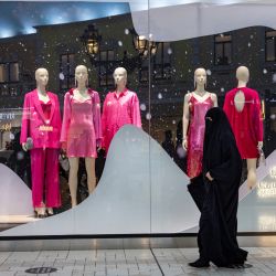Una mujer pasa por delante de la colección de invierno de una tienda de ropa femenina en el centro comercial Villagio en Doha, Qatar. | Foto:ODD ANDERSEN / AFP