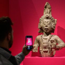 Una persona toma una foto de una escultura maya durante el preestreno para la prensa de "Vidas de los dioses: la divinidad en el arte maya" en el Museo Metropolitano de Arte de Nueva York. | Foto:ANGELA WEISS / AFP