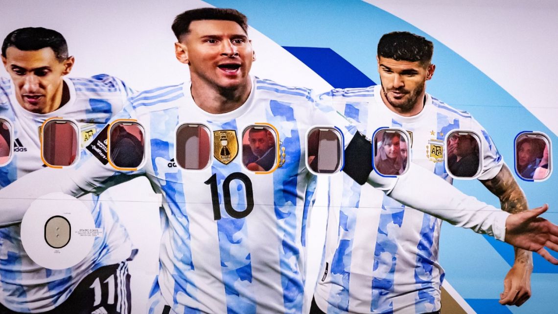 Members of the Argentinian team peer out from the windows on their plane adorned with a picture of Argentina's forward Lionel Messi and teammates as the team arrives at the Hamad International Airport in Doha on November 17, 2022.